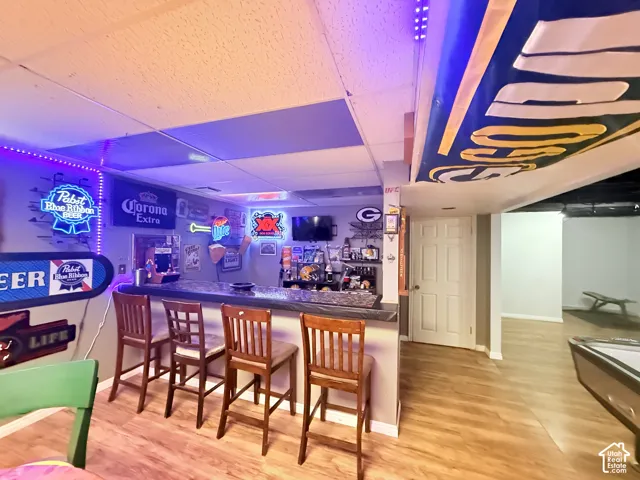 Wood-finish flooring throughout, featuring a built-in bar with a textured countertop, and recessed lighting