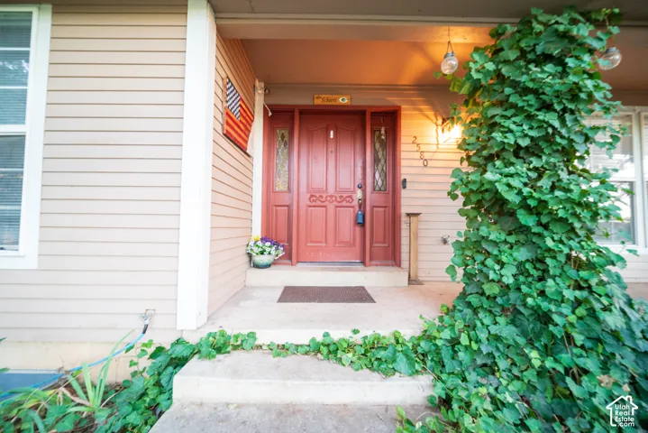 Inviting entry with a red panel door, decorative glass inserts, and a covered porch