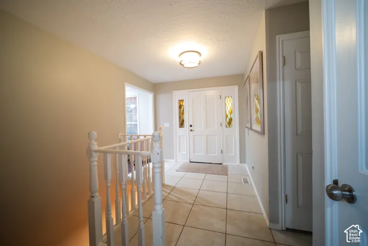 Entryway featuring tile flooring, white double entry doors with decorative glass panels, and a semi-flush mount ceiling light