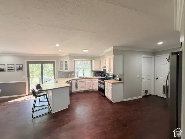 Open-concept kitchen with wood-finish flooring, white cabinetry, and stainless steel appliances