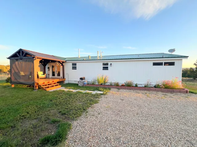 Covered wood deck with dark metal roof, white siding exterior, and a green metal roof