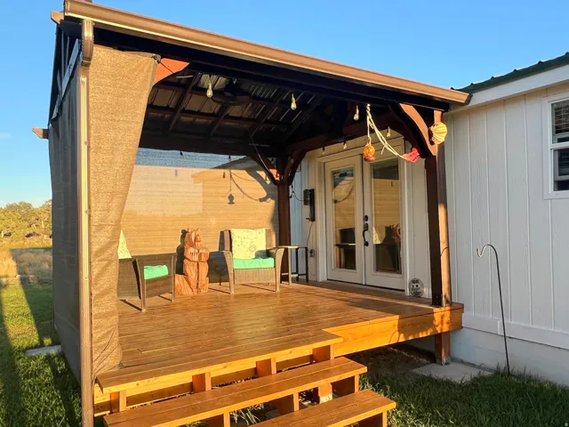 Covered wood-finish deck with privacy screens, wood steps, and double French doors