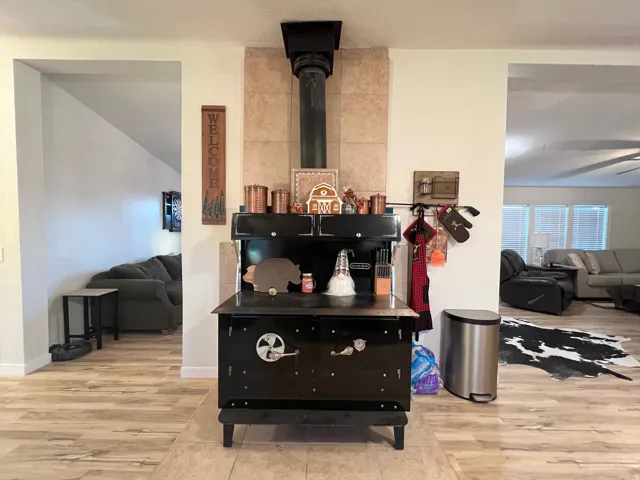 Black wood-burning stove with a tiled backdrop, wood-finish flooring, and white walls