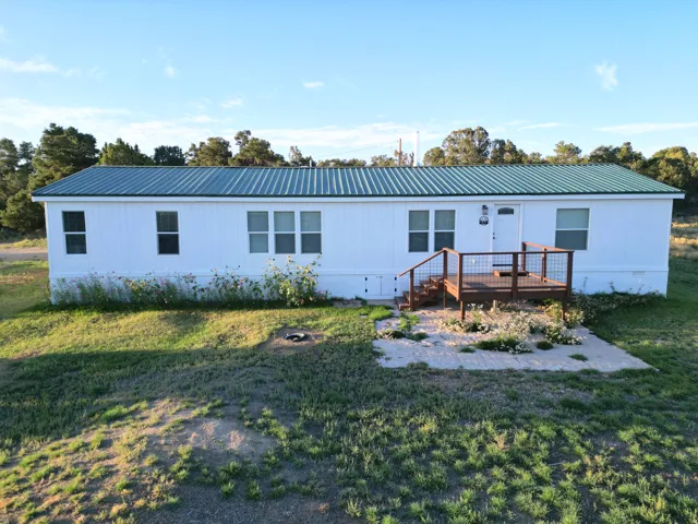 White siding exterior with a green metal roof