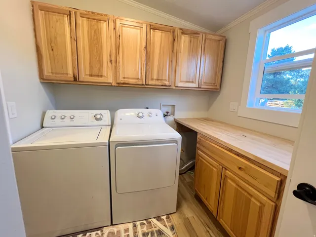 Utility room with wood-finish cabinetry, solid surface countertop, and a window