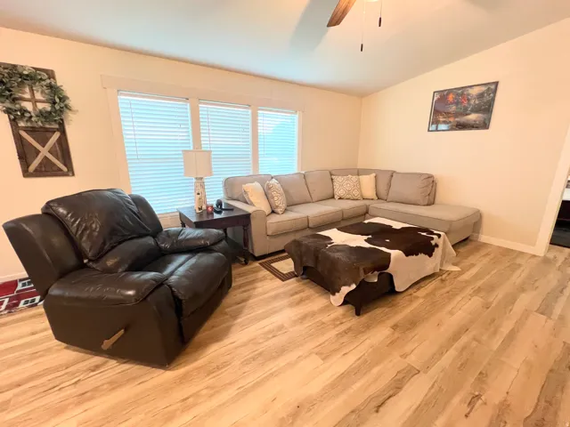 Wood-finish flooring throughout, light-toned walls, and multiple windows with blinds