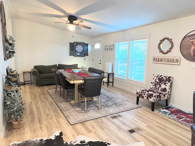 Vaulted ceiling with a ceiling fan, wood-finish flooring, white trim work, and multiple windows