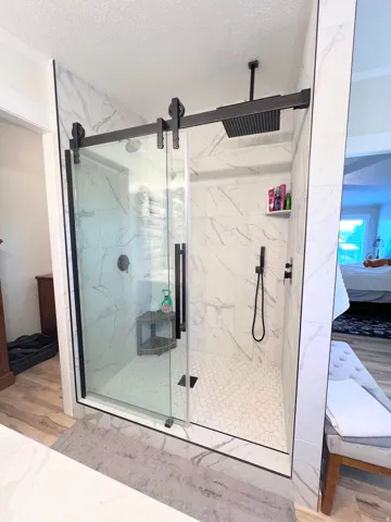 Large shower with marble-look tile surround and mosaic floor
