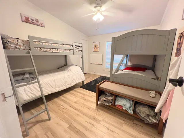 Wood-finish flooring with a ceiling fan and white walls