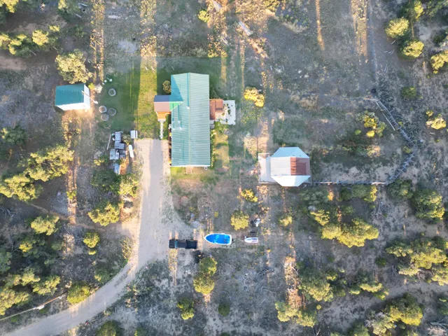 Expansive property featuring a main residence with a green metal roof, an additional outbuilding with a green metal roof, and a separate structure with a light-colored roof