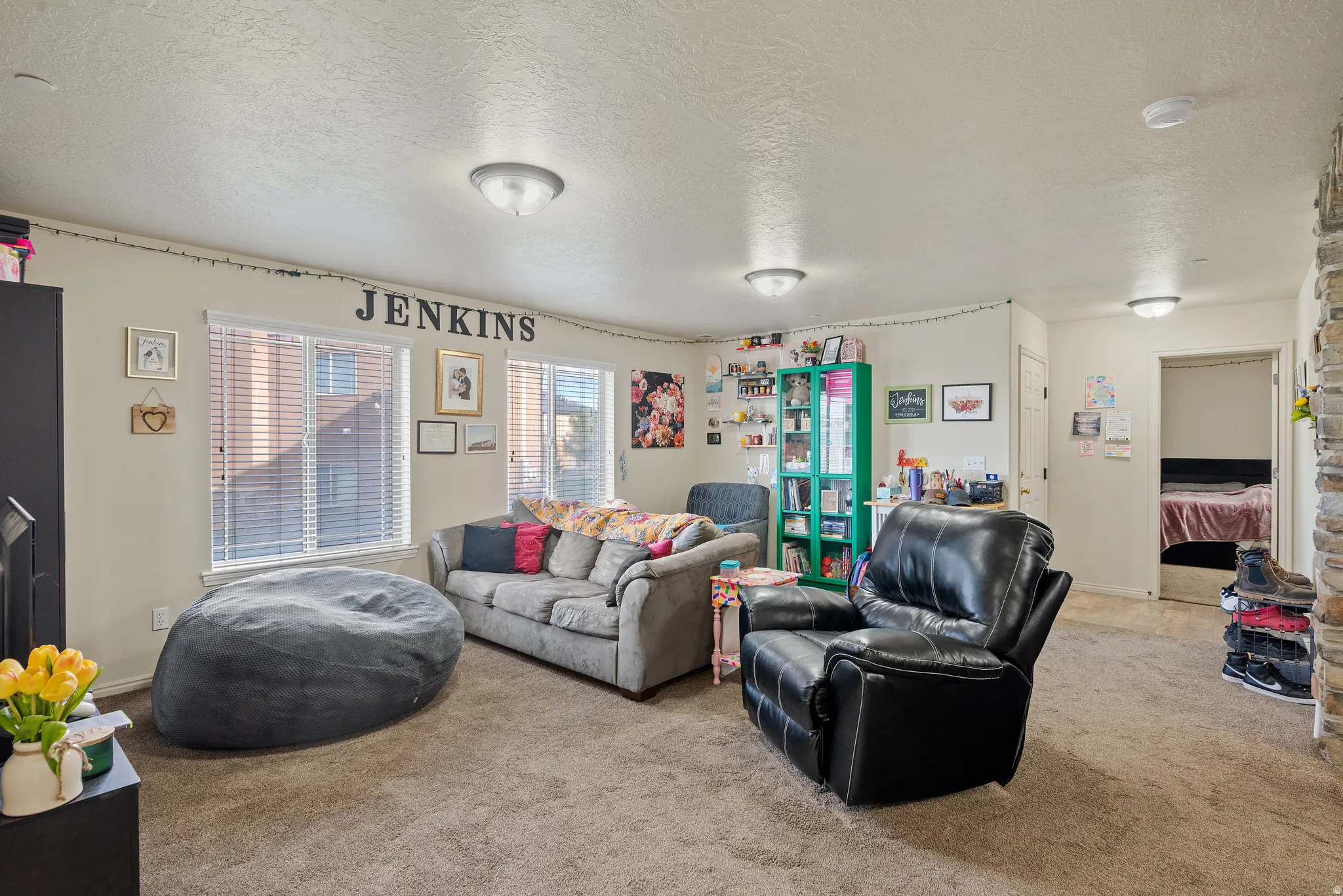 Carpeted common area featuring multiple windows with blinds, recessed lighting, and a stone-clad architectural element