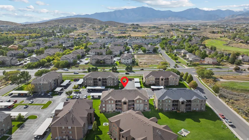 Expansive aerial perspective showcasing multi-story residential buildings, paved parking areas, and surrounding green spaces