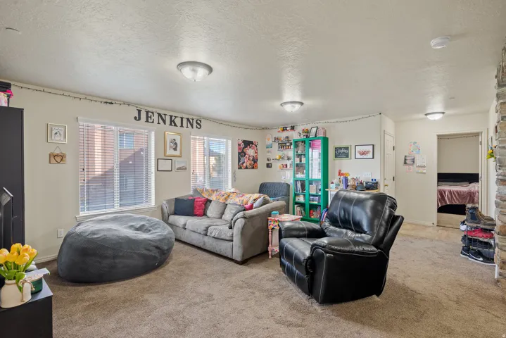 Carpeted common area featuring multiple windows with blinds, recessed lighting, and a stone-clad architectural element