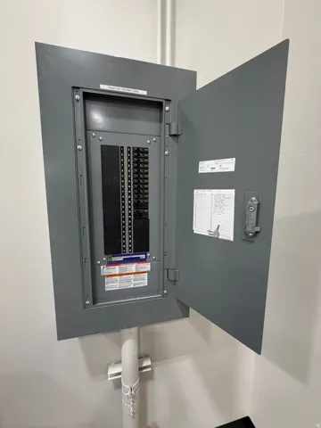 Electrical service panel with an open gray metal door