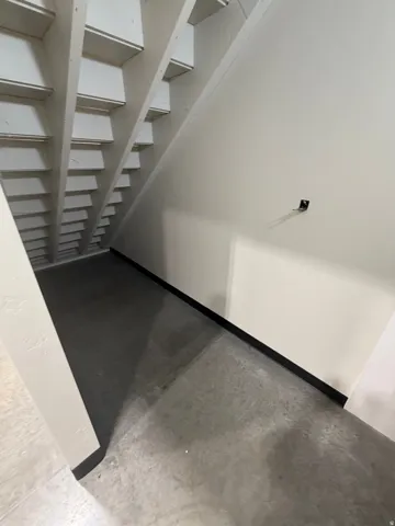 Concrete flooring with white painted walls and exposed wooden stair stringers