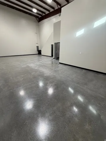Polished concrete flooring, high ceilings with exposed structural beams, white painted walls, and built-in office structure