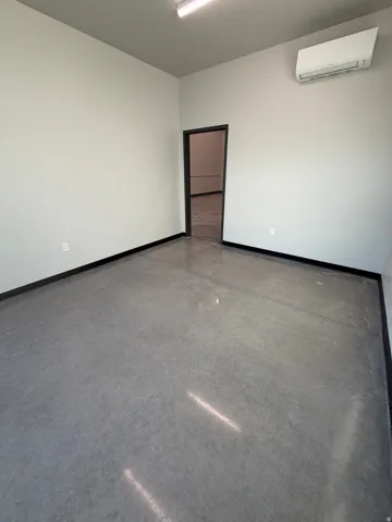Polished concrete flooring with a dark trim, light gray walls, and a wall-mounted air conditioning unit