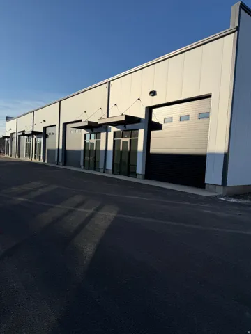 Modern commercial building with multiple bay doors, individual glass entryways, and sleek metal awnings
