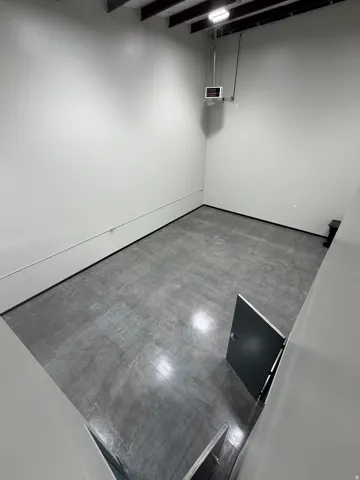 Concrete flooring with a smooth finish, exposed ceiling joists, and white painted walls
