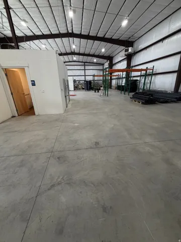 Expansive concrete flooring throughout, high ceilings with exposed structural beams, insulated ceiling panels, and integrated overhead lighting