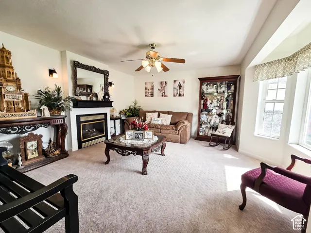 Living space featuring a fireplace with a black mantel, an ornate mirror, a ceiling fan, and a bay window with valance