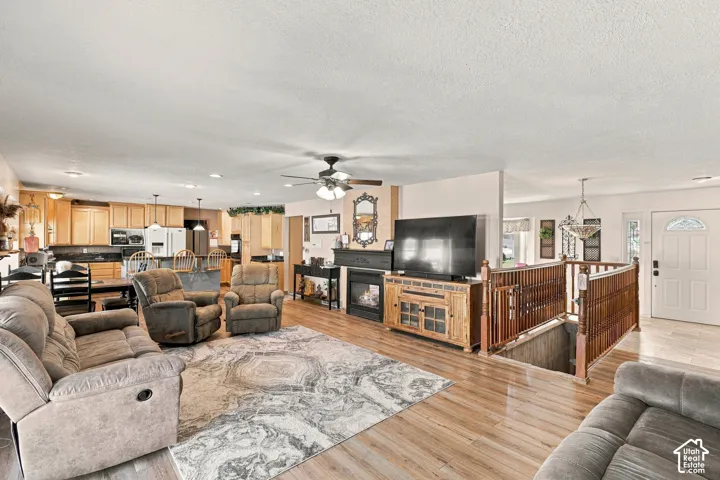 Open-concept living space featuring wood-finish flooring, a ceiling fan, and a built-in fireplace