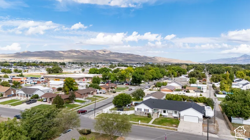 Residential neighborhood featuring mature trees, paved streets, and mountain backdrops