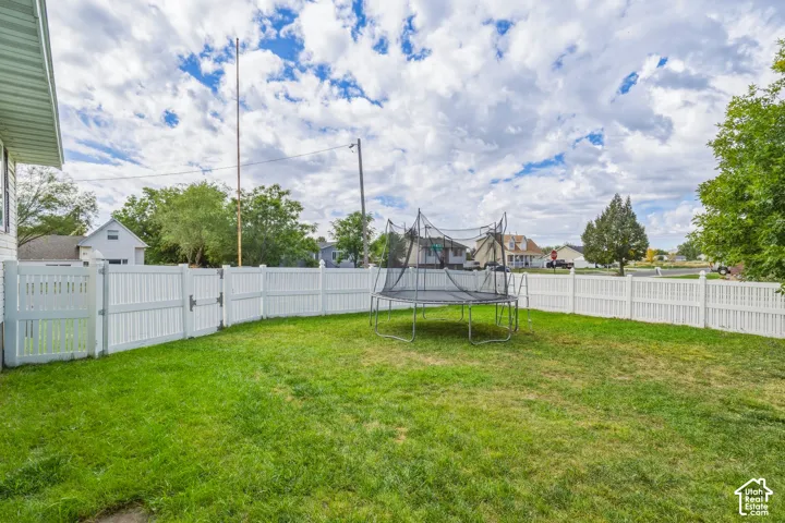 Expansive lawn area with a white privacy fence and a gated entry
