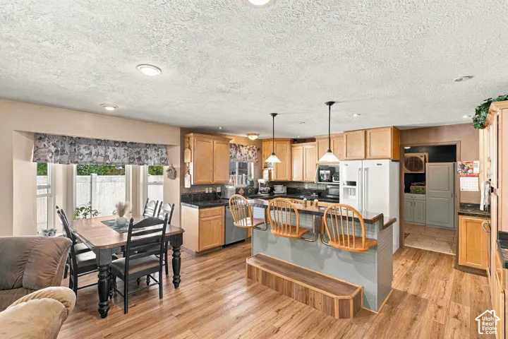 Open-concept kitchen and dining area featuring wood-finish flooring, recessed lighting, and a bay window