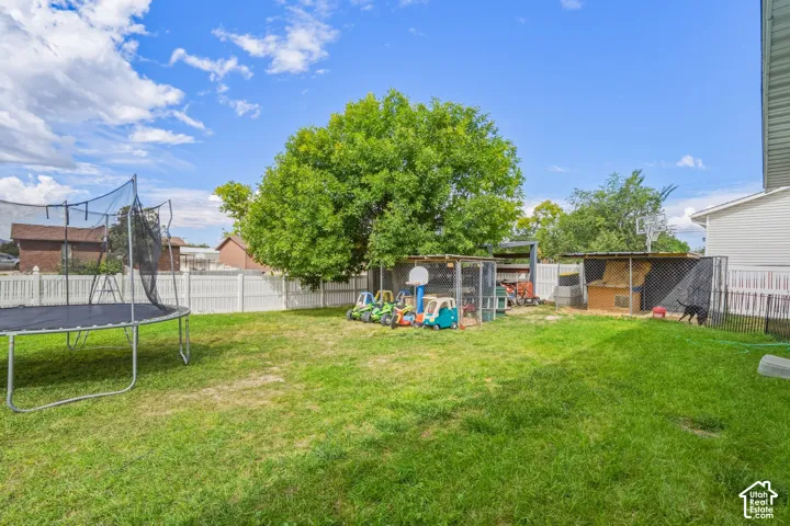 Expansive grass lawn with a white privacy fence and mature trees