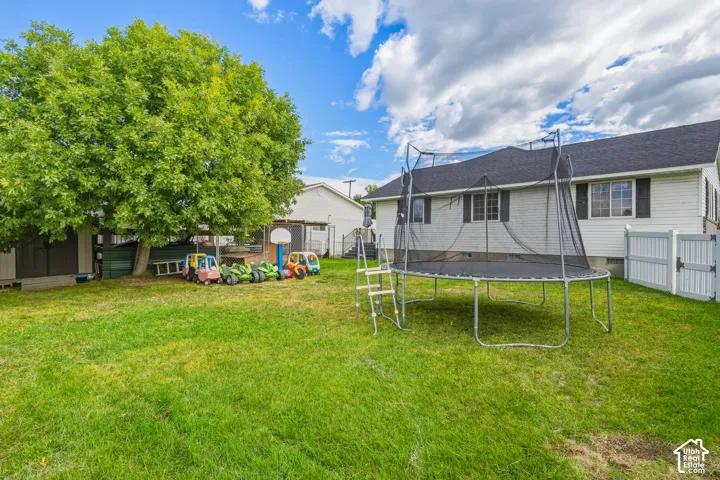 Expansive green lawn featuring mature trees, a private fenced area, and a classic residential exterior with multiple windows