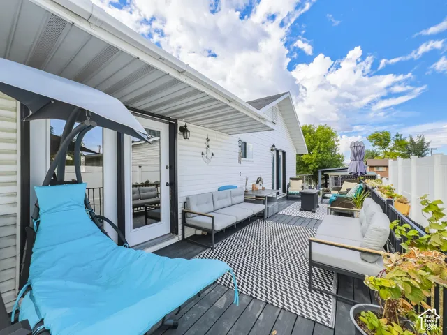 Spacious outdoor deck with dark wood-finish flooring, white vinyl siding, and a white privacy fence