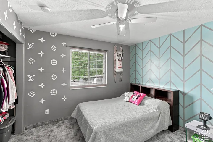 Built-in closet shelving, window with blinds, ceiling fan, and painted accent walls