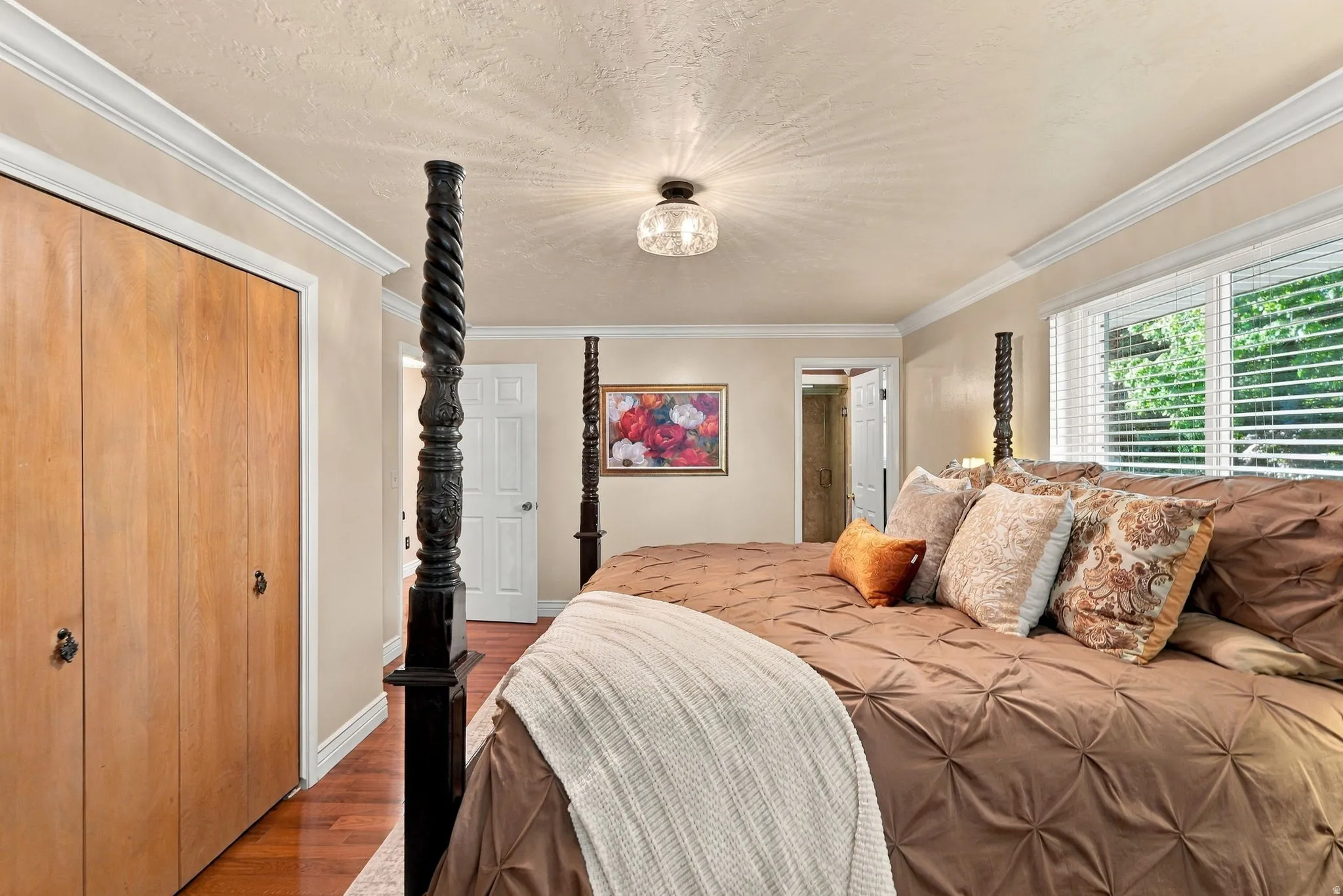 Wood-finish flooring, crown molding, and a built-in closet with natural wood doors