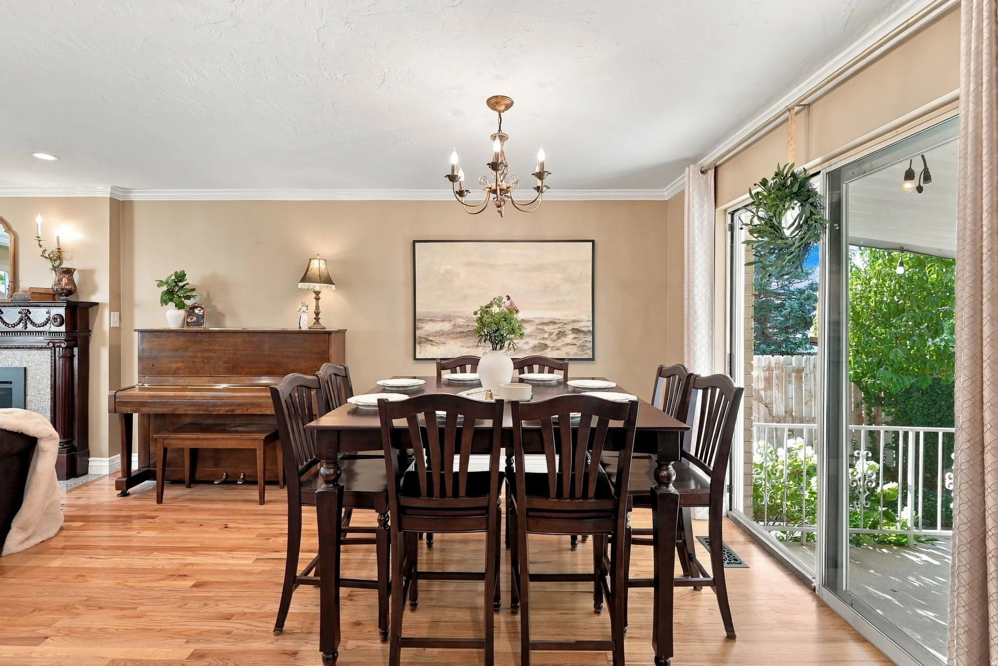 Wood-finish flooring, crown molding, fireplace with mantel, sliding glass door, and a multi-light chandelier