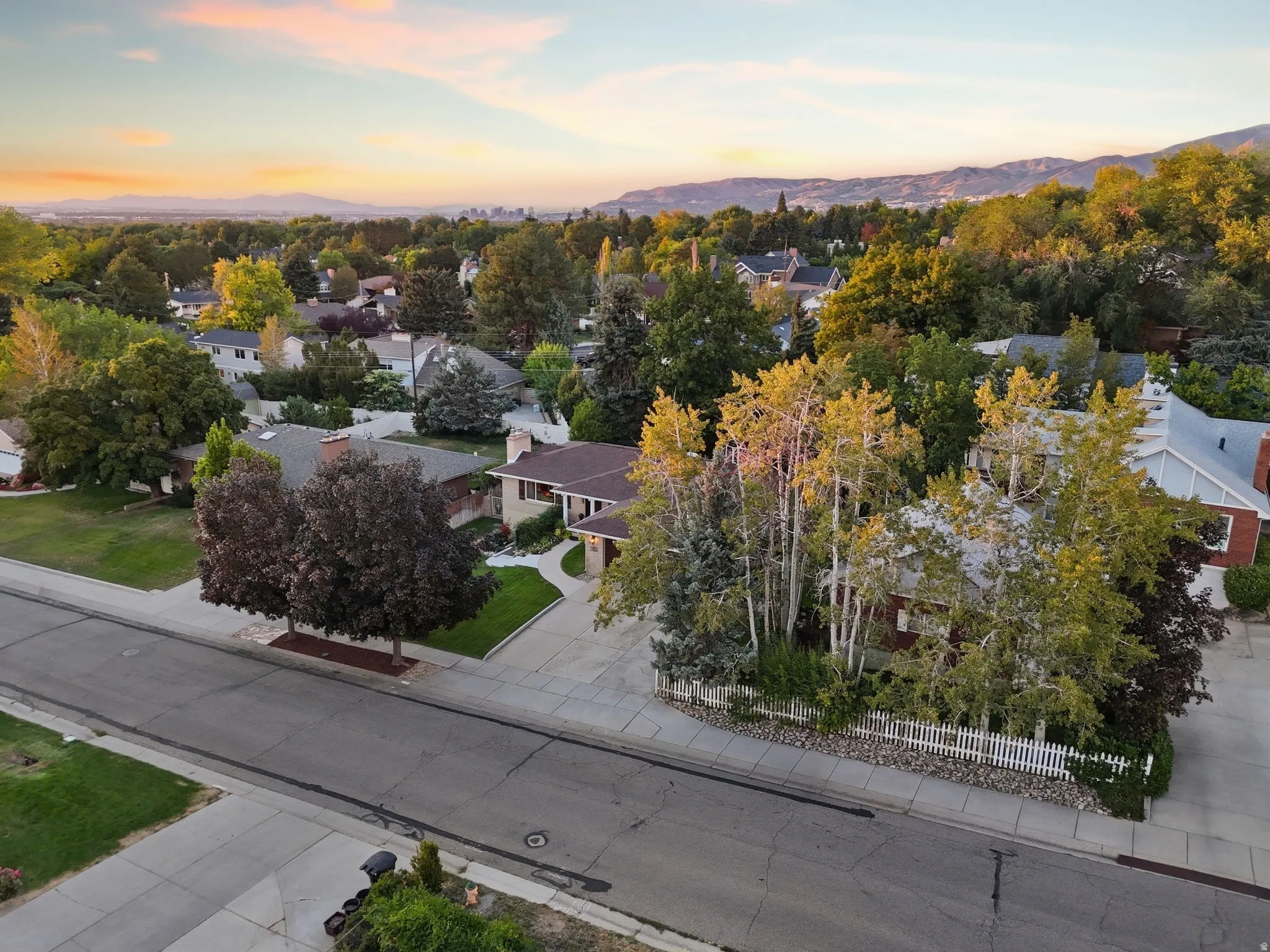 Suburban neighborhood setting with mature trees and mountain backdrop