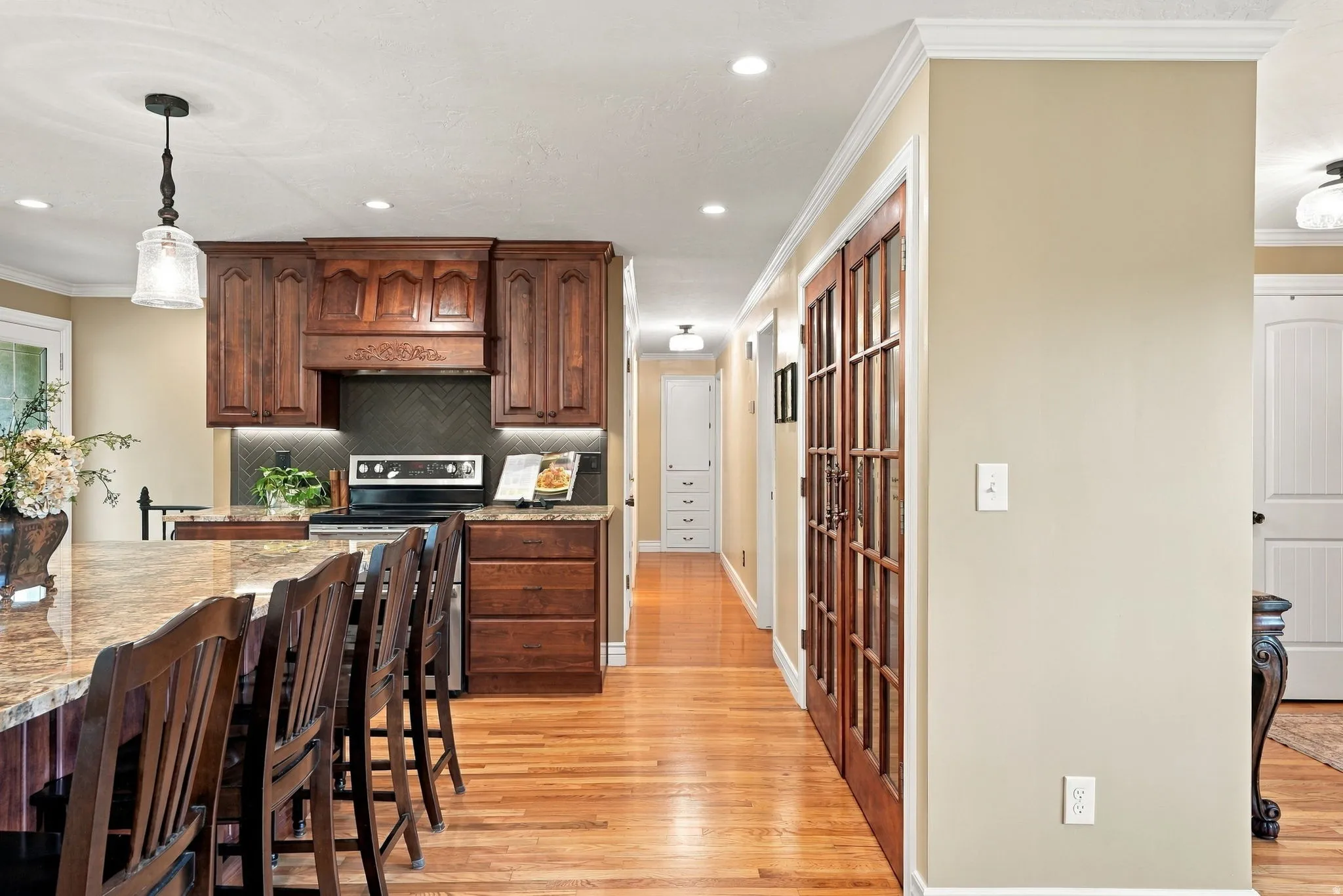 Kitchen featuring rich wood cabinetry, granite countertops, and a herringbone tile backsplash