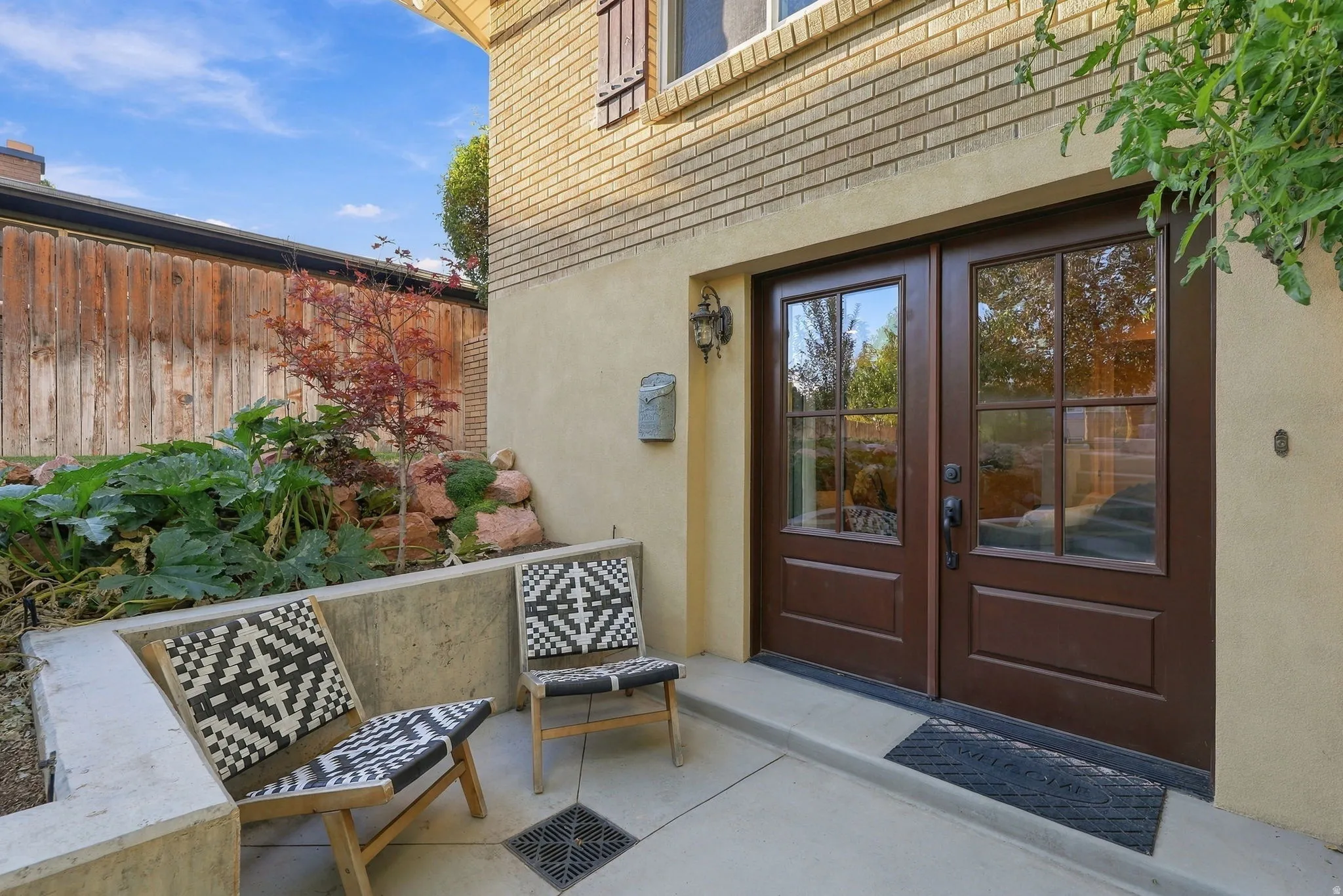 Double-paned glass-panel entry doors with dark hardware, set into a stucco exterior with a brick upper level