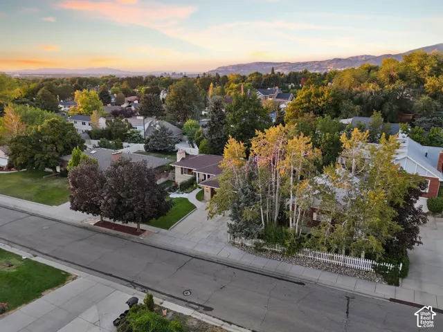 Suburban neighborhood setting with mature trees and mountain backdrop