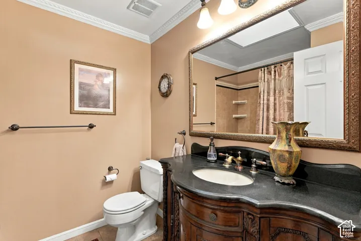 Bathroom featuring an ornate wood vanity with an undermount sink, dark countertop, and a framed mirror with integrated lighting