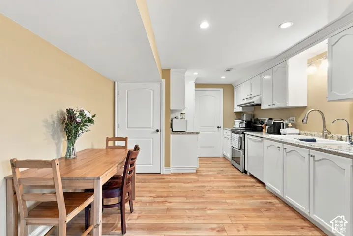 Wood-finish flooring throughout, white cabinetry with crown molding, stainless steel kitchen appliances, and recessed ceiling lighting