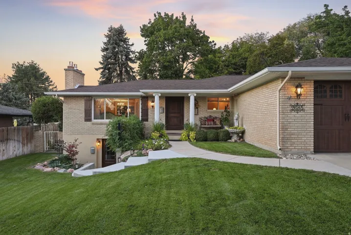 Brick exterior with a prominent chimney, dark wood garage door, and a concrete walkway