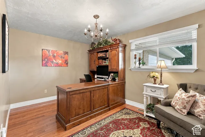 Hardwood flooring, crown molding, white window trim, and a chandelier lighting fixture
