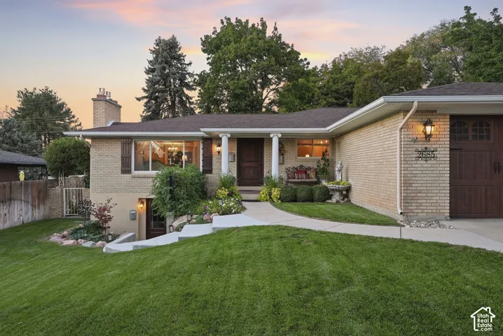 Brick exterior with a prominent chimney, dark wood garage door, and a concrete walkway
