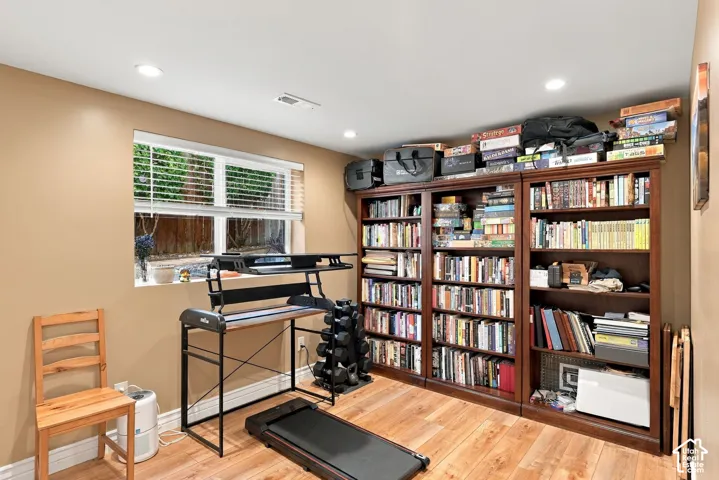 Wood-finish flooring, built-in shelving units, recessed lighting, and a window with blinds