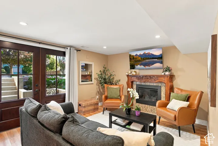 Warm living space featuring rich wood-finish flooring, recessed lighting, and a stone-clad fireplace with an ornate mantel