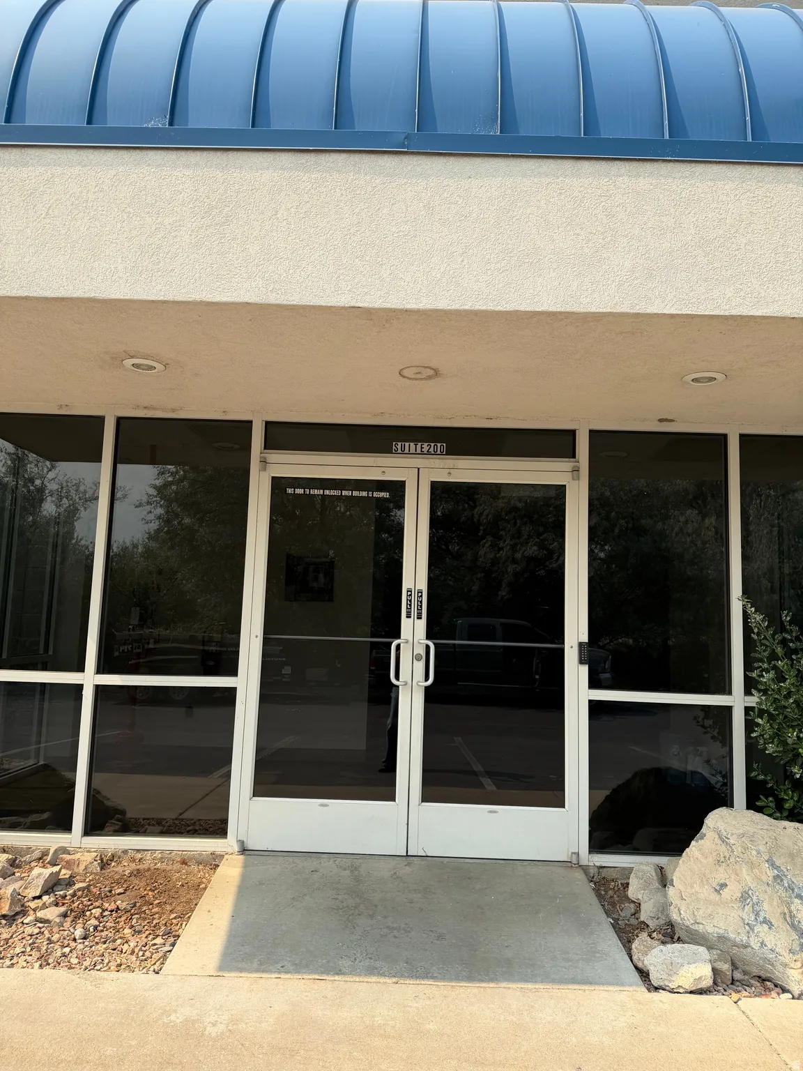 Entryway featuring double glass doors, a blue curved roof, recessed lighting, and surrounding tinted windows