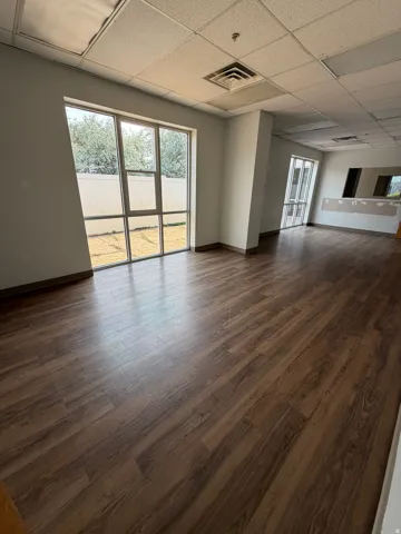 Wood-finish flooring, drop ceiling with integrated lighting, and multiple large windows with exterior access