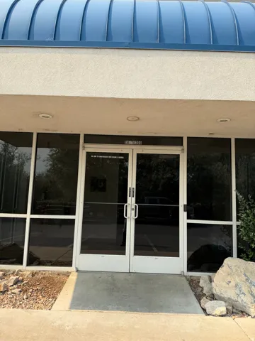 Entryway featuring double glass doors, a blue curved roof, recessed lighting, and surrounding tinted windows