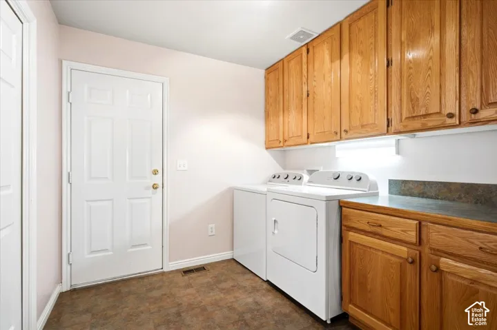 Laundry area featuring overhead wood cabinetry, a built-in counter, and durable flooring